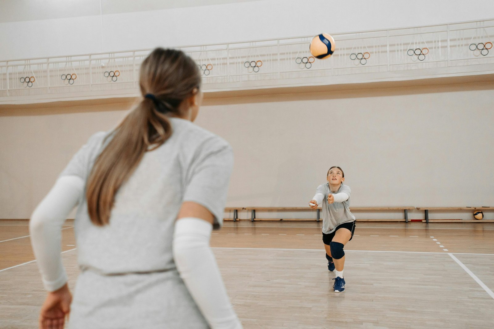 Women practicing volleyball indoors, focused on ball control and teamwork.